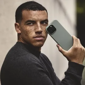 Mujjo Lederhülle für das iPhone 16 Pro Max in Rauchgrün, gezeigt an einem Smartphone in einem Lifestyle-Porträt.