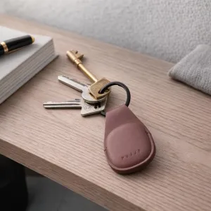 Mujjo Leather AirTag Keychain aus braunem Leder mit befestigten Schlüsseln und geprägtem Logo auf einer Holztischplatte