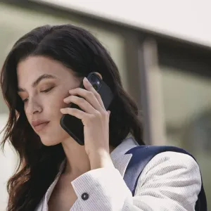 Mujjo Lederhülle mit MagSafe für iPhone 14 Pro Max in Schwarz, gezeigt an einem Smartphone, das sie ans Ohr hält