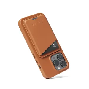 Porte-cartes en cuir MagSafe Mujjo couleur fauve, fixé à une coque iPhone assortie avec une carte visible.