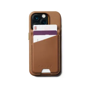 Portefeuille-support en cuir MagSafe Mujjo couleur fauve fixé à un iPhone, contenant plusieurs cartes