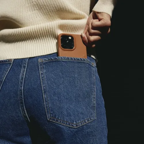 Mujjo Lederhülle für iPhone 14 mit Kartenaufbewahrung und Kameraschutz, in eine Jeanstasche gesteckt.