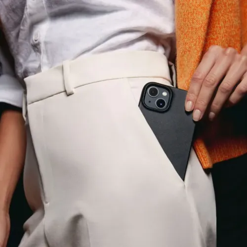 Coque Mujjo en cuir noir pour iPhone 14 avec découpe pour l’appareil photo et profil fin, présentée glissée à la ceinture
