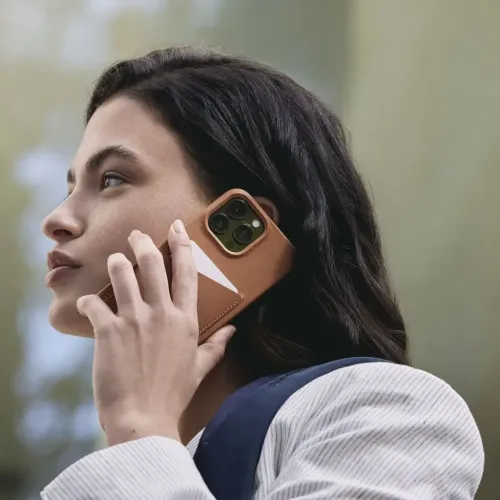 Étui portefeuille en cuir Mujjo pour iPhone 14 avec poche pour carte et découpe surélevée pour l’appareil photo, tenu contre le visage d’une personne
