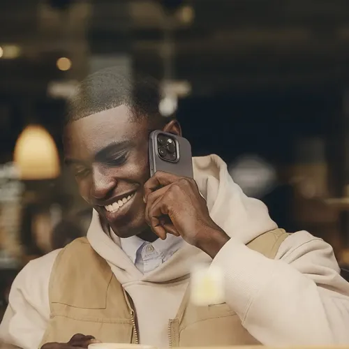 Mujjo iPhone 15 Pro-etui i stålblå med overflade, slank profil og hævet kameraramme; synligt på telefonen under brug.