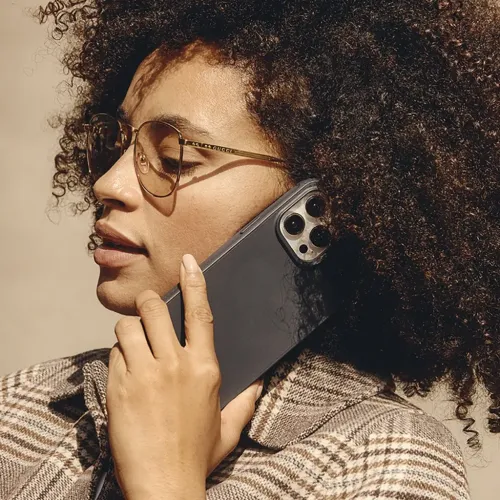 Stålblå Mujjo Impact Case til iPhone 15 Pro Max med slank profil og hævet kameraramme, vist med telefonen holdt op til øret.