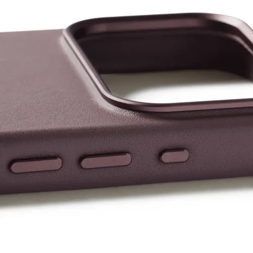 Pronssinpunainen nahkakotelo iPhonelle, jossa on kolme pitkulaista metallista sivupainiketta ja korotettu neliönmuotoinen kamerakehys, kuvassa terävässä lähikuvassa.